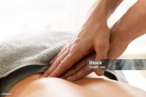 Closeup of masseur man’s hands during back massage for his woman client